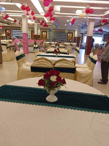 a banquet hall with tables and chairs with a vase of flowers at Hotel Highway Greens Near VR Punjab Mall Airport Road Mohali Chandigarh in Mohali