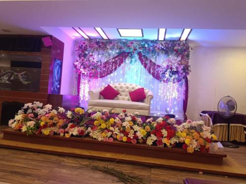 a room with a stage with a couch and flowers at Hotel Highway Greens Near VR Punjab Mall Airport Road Mohali Chandigarh in Mohali