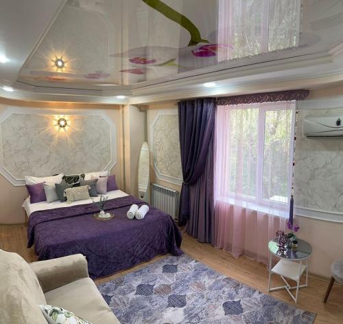 a bedroom with a purple bed and a window at Уютный уголок in Shymkent