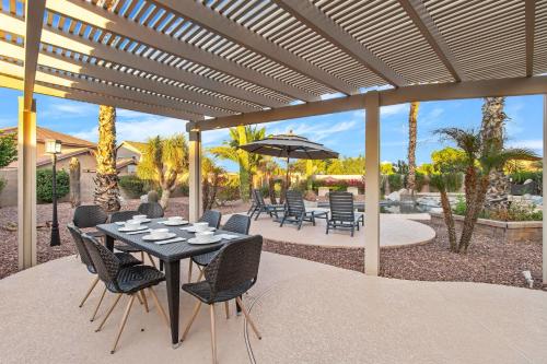 a table with chairs and an umbrella on a patio at Monte Cristo Home - Epic Backyard Pool Spa & Firepit in Surprise