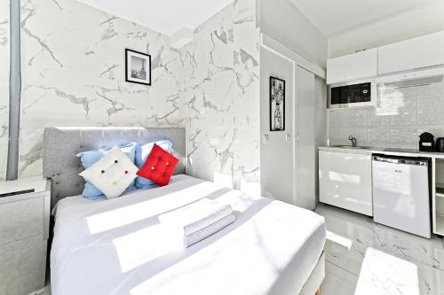 - une chambre blanche avec un grand lit et un mur en marbre dans l'établissement Studio Les Lilas, aux Lilas