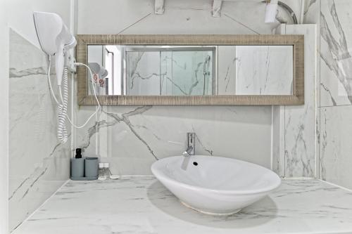 une salle de bain blanche avec un lavabo et un miroir dans l'établissement Studio Les Lilas, aux Lilas