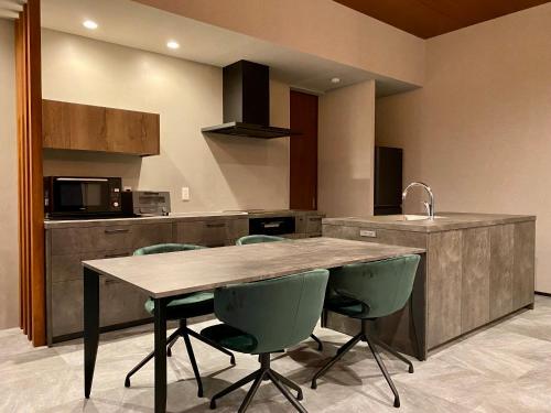 a kitchen with a wooden table and green chairs at The Park Villa in Ichinomiya