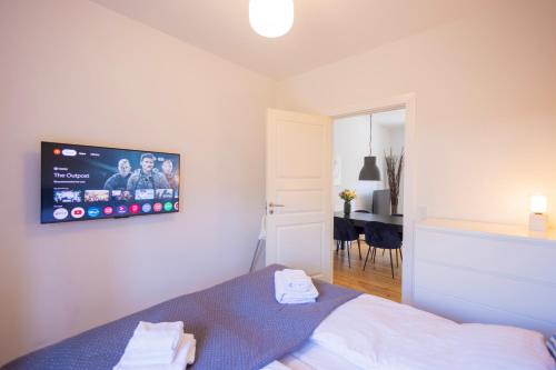 a bedroom with a bed with a tv on the wall at Central Lyngby Apartments in Kongens Lyngby