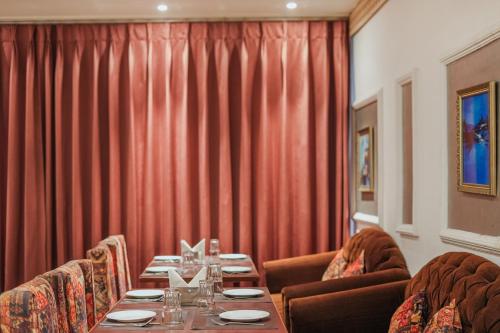a dining room with a long table and red curtains at Hotel Highway Greens Near VR Punjab Mall Airport Road Mohali Chandigarh in Mohali