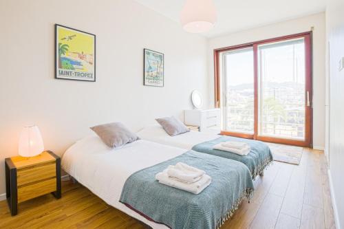 une chambre avec deux lits et une grande fenêtre dans l'établissement Fully AC, Port-view, 2 min beach and Palais, à Cannes
