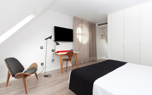 a bedroom with a bed and two chairs and a desk at Vértice Sevilla in Seville