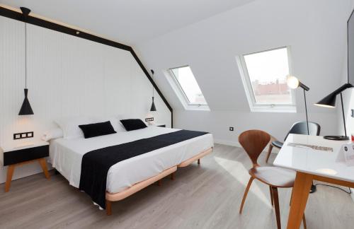 a bedroom with a bed and a desk and a chair at Vértice Sevilla in Seville