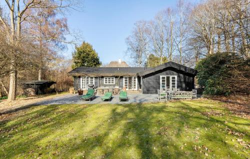 a log cabin with green chairs in front of it at Lovely Home In Tisvildeleje With Sauna in Tisvildeleje
