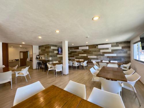 a restaurant with wooden tables and white chairs at Hotel Star in Manzanillo