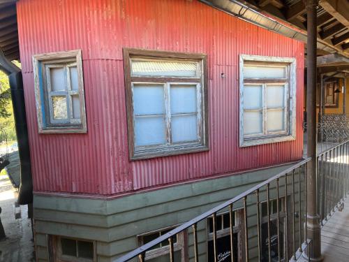 three windows on the side of a red house at Mercado NicoLore in Villa La Angostura