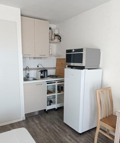 une petite cuisine avec un réfrigérateur et un micro-ondes dans l'établissement Studio cosy pour curistes avec terrasse, vue sur piscine, à Balaruc-les-Bains