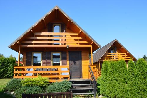 a wooden house with a staircase leading to it at Domki Pod Lasem in Polańczyk