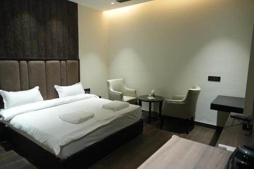 a bedroom with a bed and a desk and chairs at Hotel The Royalista in Bathinda