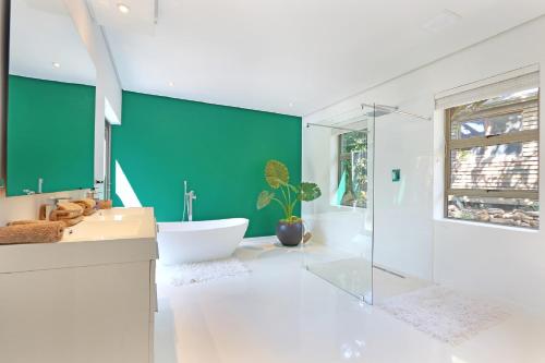 a bathroom with a tub and a green wall at Valtameri by Totalstay in Cape Town