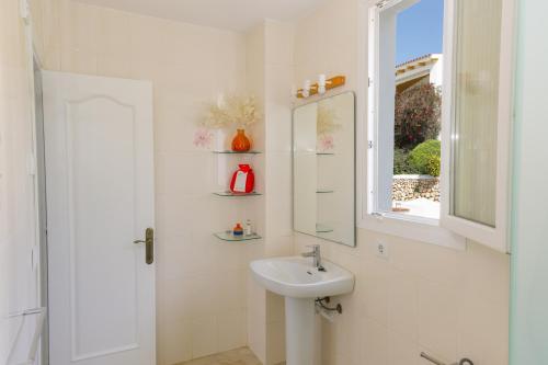 une salle de bain blanche avec un lavabo et un miroir dans l'établissement Villa Zodiaco Aries, à Son Bou