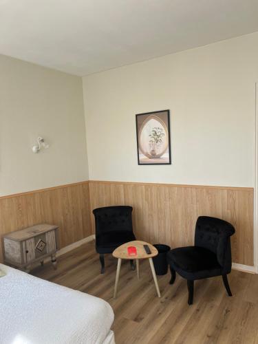 a room with two chairs and a table and a bed at Hôtel Les Quais in Cherbourg en Cotentin