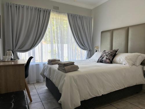 a bedroom with a large bed with a large window at AfriSky guest house in Kempton Park