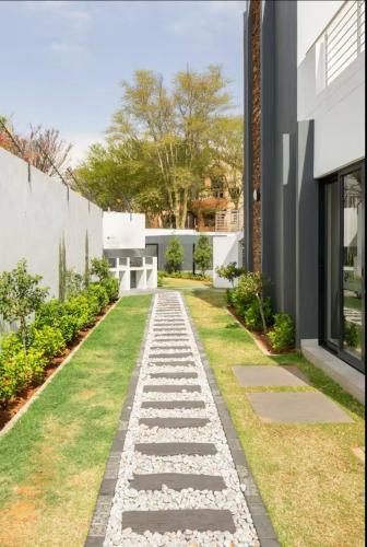 a garden path with rocks and grass in front of a house at Exquisite Classy 1 bed in Midrand at 93 on New Lifestyle Estate in Midrand