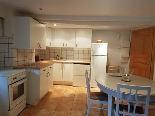 une cuisine avec des armoires blanches et une table avec des chaises dans l'établissement Chez Maria, à Turckheim