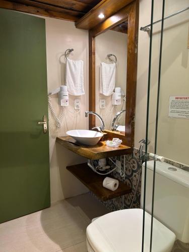 a bathroom with a sink and a mirror and a toilet at Pousada Charm Canela in Canela