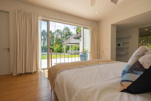 a bedroom with a bed and a large window at Top Pool Villa Layan Estate Laguna Bangtao in Layan Beach