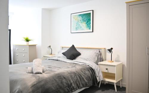 a white bedroom with a bed and a night stand at Modern, Spacious, Central 2-Bed Plymouth Apartment in Plymouth