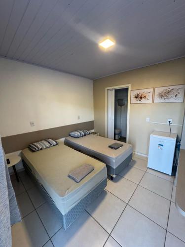a room with two beds and a refrigerator in it at Villa Germânia - Pousada da Luiza in Santa Cruz do Sul