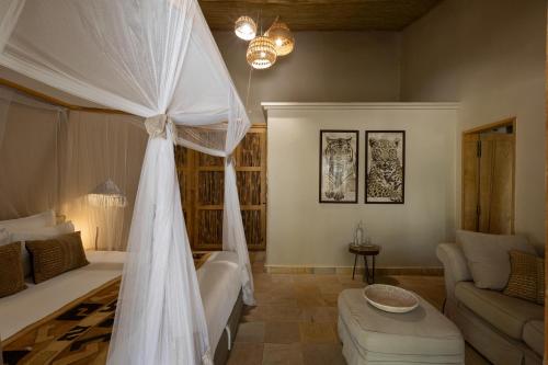 a bedroom with a bed with a white canopy at Les Palétuviers in Toubakouta