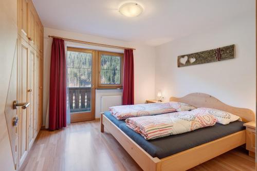 a bedroom with a bed with red curtains and a window at Sprenghof Ferienwohnung in Sarntal