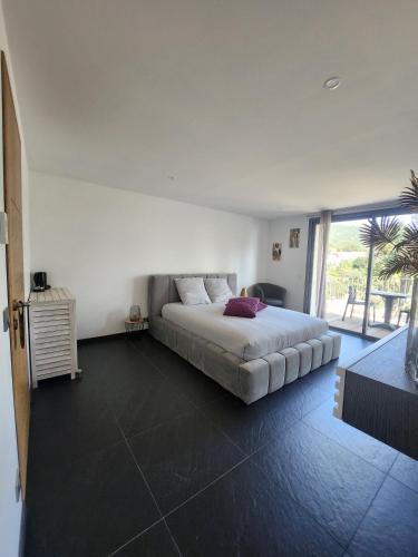 une chambre avec un lit et une grande fenêtre dans l'établissement Villa l’écrin du Rayol, à Rayol-Canadel-sur-Mer