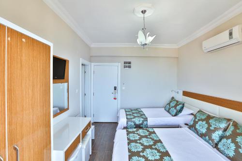 a hotel room with two beds and a tv at Hotel Kayahan in Kas