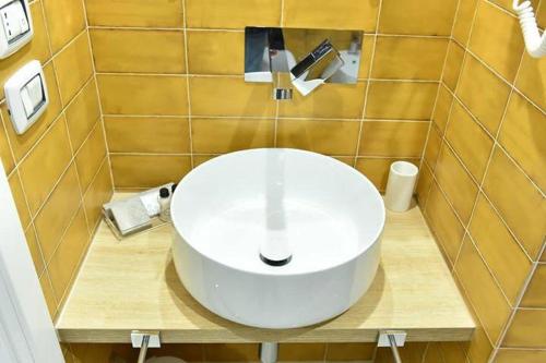 a bathroom with a white sink on a tiled wall at Carlotta Rooms in Conversano