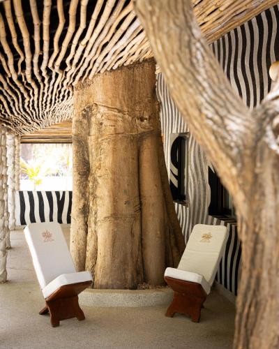 two white chairs in a room with a pillar at Les Palétuviers in Toubakouta