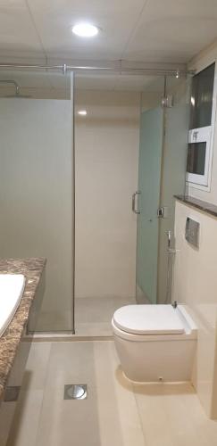 a bathroom with a toilet and a glass shower at Al Wahda Private Couples Room in Abu Dhabi