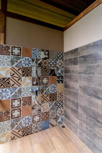 a bathroom with a tiled wall with a shower at Corcovado Accommodations-pool-best views-nature in Puerto Jiménez