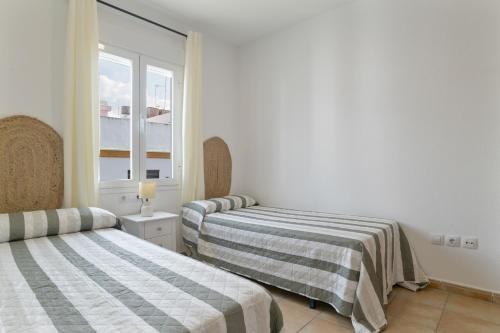 two beds in a room with a window at Apartamento Perez Zara 6 in Conil de la Frontera