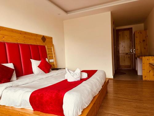 a bedroom with a large bed with a red headboard at Hotel Pine Grove in Manāli