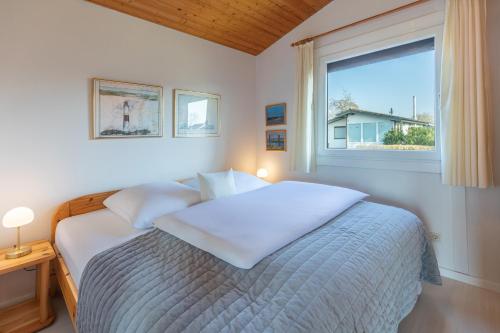 Un dormitorio blanco con una cama con ventana. en Deichblick, en Simonsberg