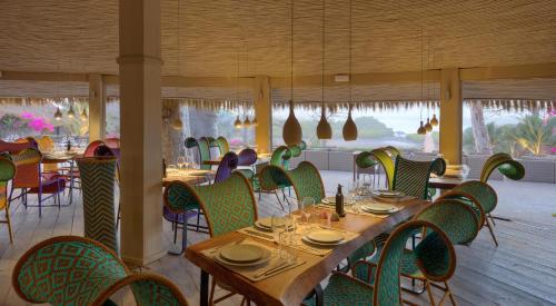 a restaurant with a long table and chairs with plates and glasses at Les Palétuviers in Toubakouta