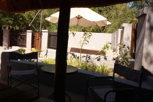 a table and chairs and an umbrella on a patio at Off Beat Safaris Bush Lodge in Hoedspruit