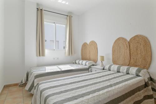 2 łóżka w pokoju z białymi ścianami i oknem w obiekcie Apartamento Perez Zara 7 w mieście Conil de la Frontera
