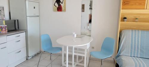 une petite cuisine avec une table blanche et des chaises bleues dans l'établissement Cap d'Agde Antinea, Plage Rochelongue, Piscine et Parking, au Cap d'Agde