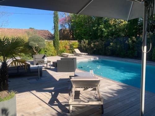 un patio avec des chaises et une piscine avec un parasol dans l'établissement Villa Soleil Bordeaux 4 chambres, à Le Bouscat