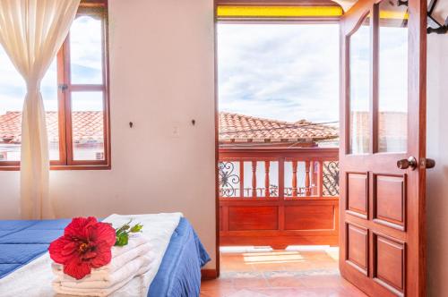 a bedroom with a bed with a red flower on it at HOTEL RUTA 40 VILLA DE LEYVA in Villa de Leyva