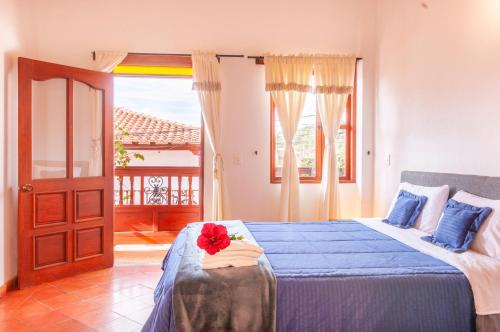 Un dormitorio con una cama azul con una flor roja. en HOTEL RUTA 40 VILLA DE LEYVA, en Villa de Leyva