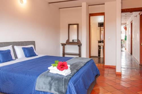 a bedroom with a blue bed with a red flower on it at HOTEL RUTA 40 VILLA DE LEYVA in Villa de Leyva