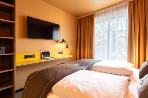 a bedroom with a bed with a tv and a window at Holiday Inn - the niu, Flux Passau by IHG in Passau