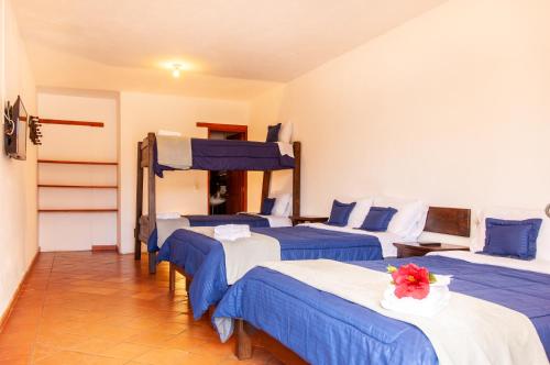a room with four beds with blue and white sheets at HOTEL RUTA 40 VILLA DE LEYVA in Villa de Leyva