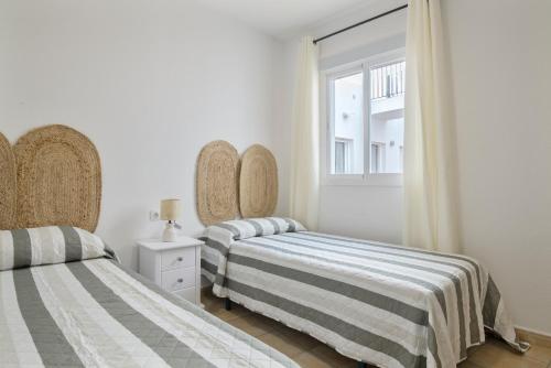 a bedroom with two beds and a window at Apartamento Perez Zara 4 in Conil de la Frontera